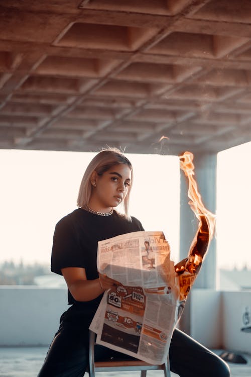 A Woman Holding a Burning Newspaper
