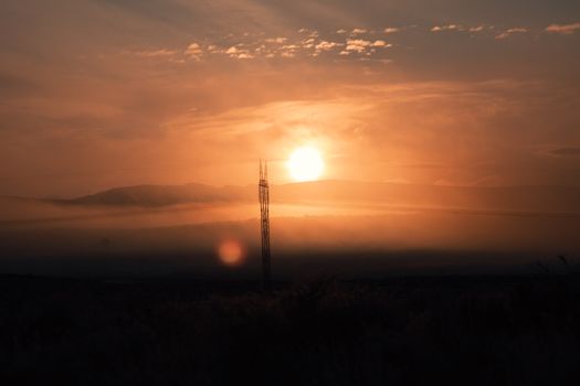 Beautiful sunrise over Idaho hills, casting golden hues across the sky with silhouetted power lines.