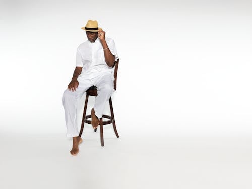 A Fashionable Man Posing while Sitting on a Chair