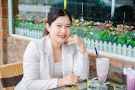 Woman in White and Pink Blazer Sitting beside a Table