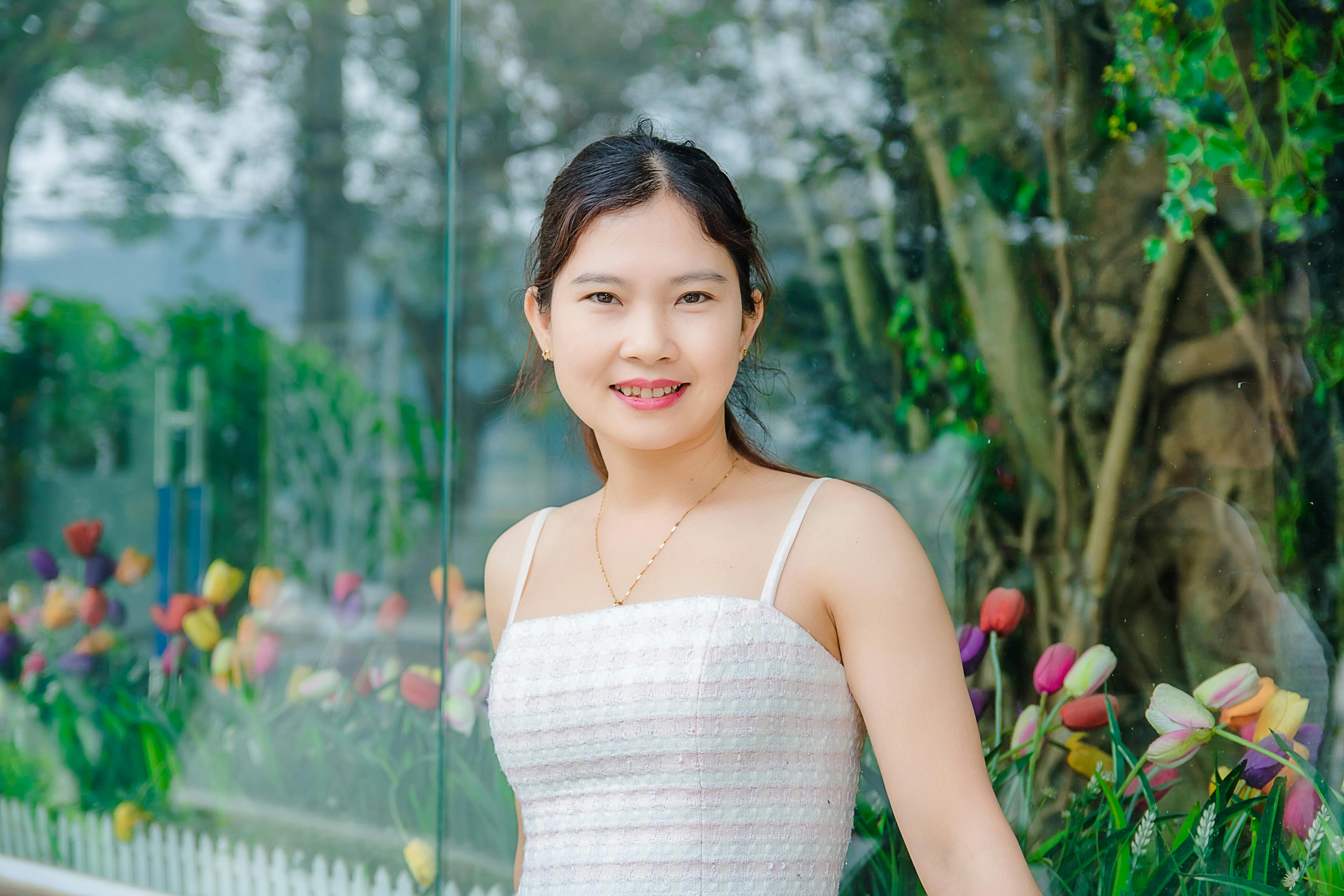Young woman smiling with colorful flowers in outdoor setting, conveying happiness.