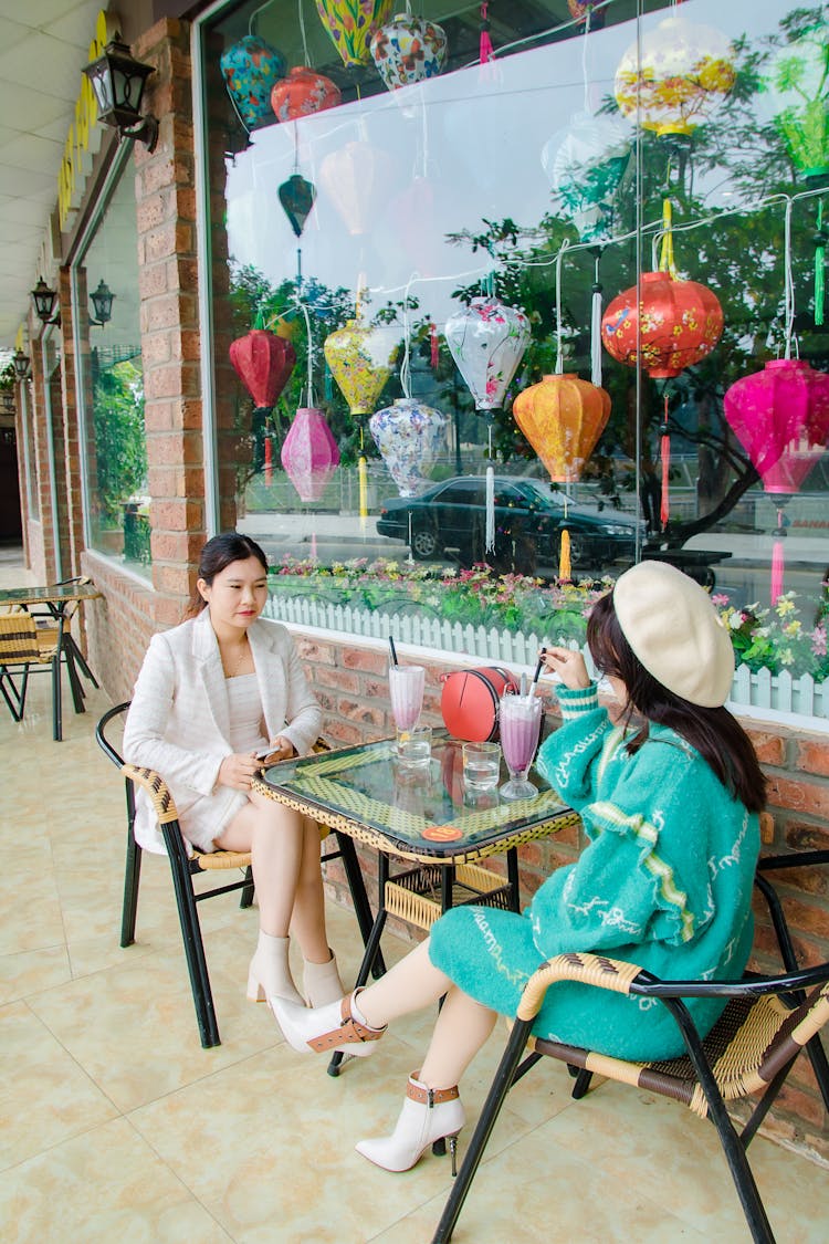 Women Sitting Outside The Restaurant While Drinking Smoothies