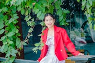 Woman in Red Jacket Sitting Beside Green Plant
