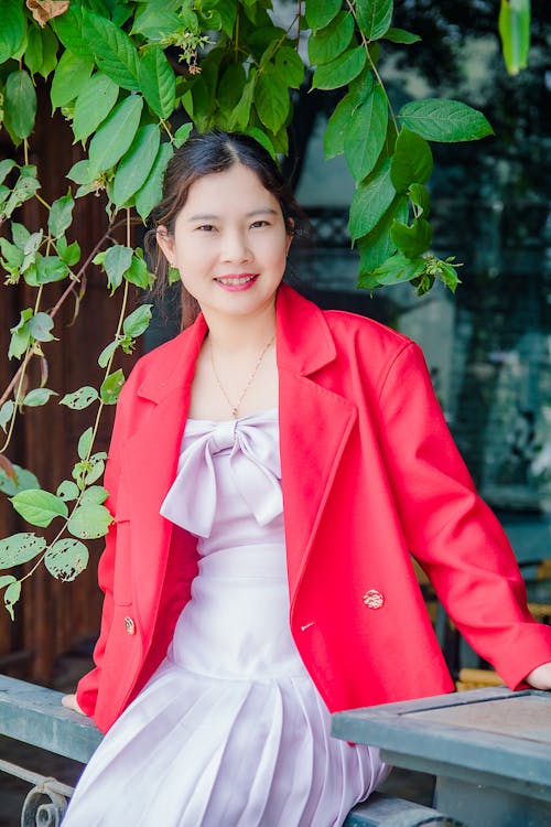 Free A Woman in Red Blazer Sitting Near Green Plant Stock Photo