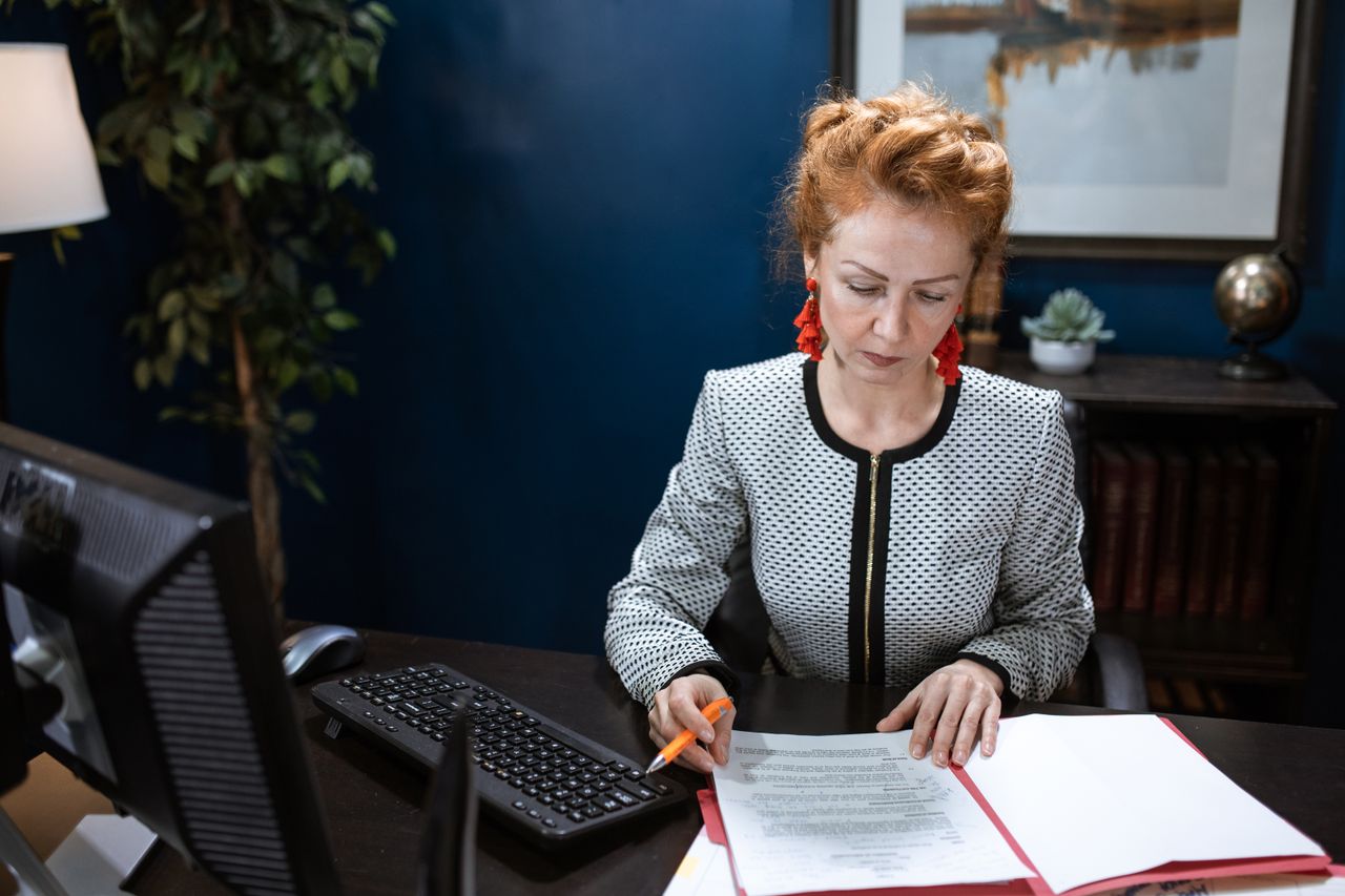 Woman wearing a black and white patterned knit cardigan jacket while working at her desk