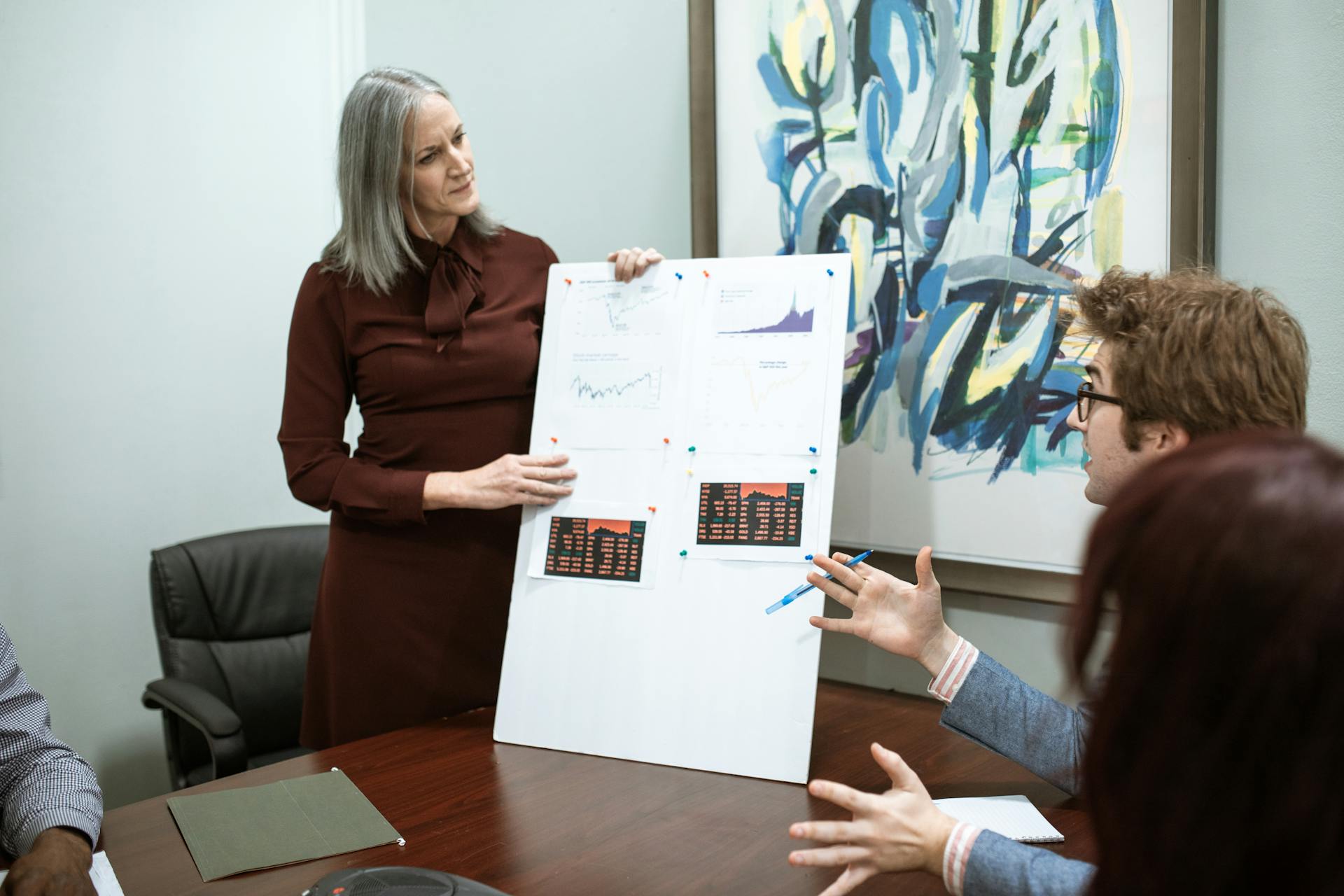 Business professionals discussing graphs during a meeting presentation in a modern conference room.