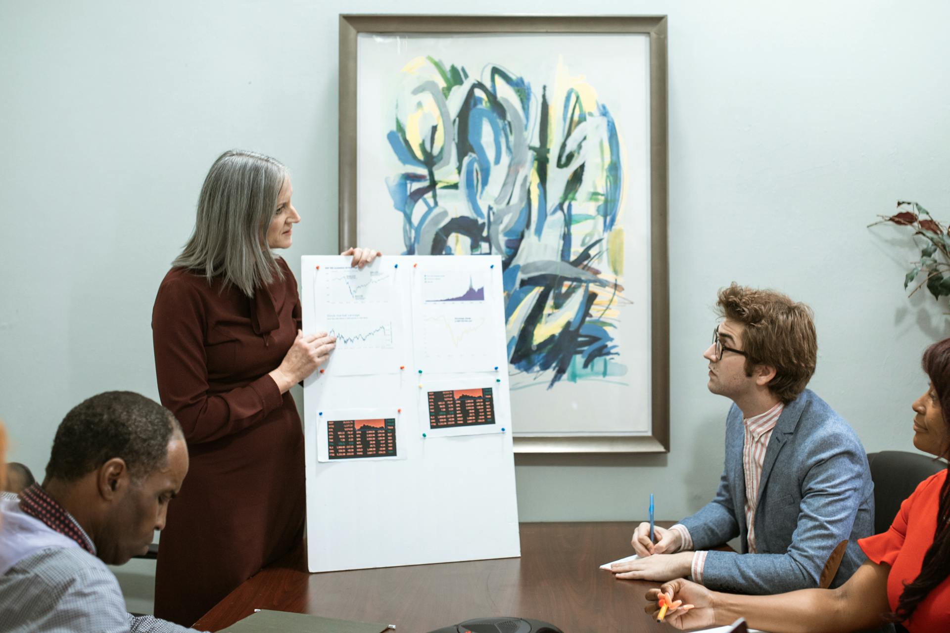 A business meeting scenario with diverse team members discussing graphs and future strategies in an office setting.