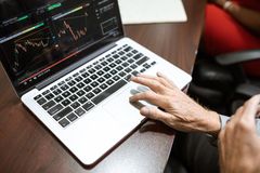 Close-up of hand using laptop for stock market analysis in office setting.