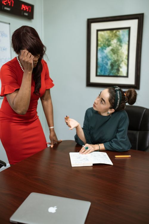 Free Two businesswomen discussing work at a desk, showcasing teamwork and collaboration. Stock Photo
