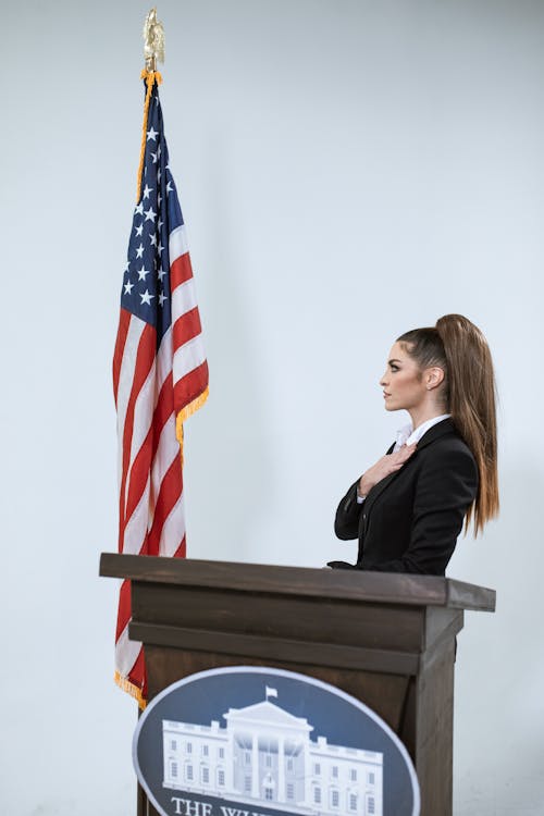 Woman in Black Blazer Standing Beside the US Flag
