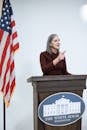 Woman in Maroon Dress Speaking Behind a Podium
