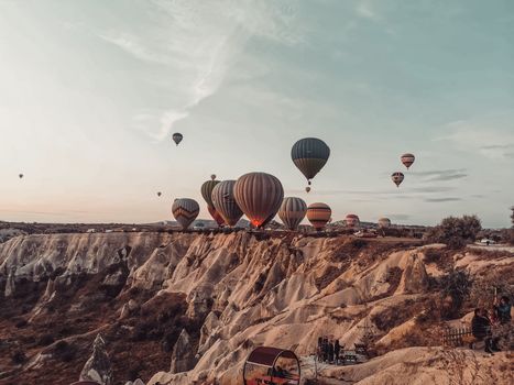 Breathtaking view of hot air balloons soaring over the distinctive rock formations of Cappadocia, Türkiye at dawn.