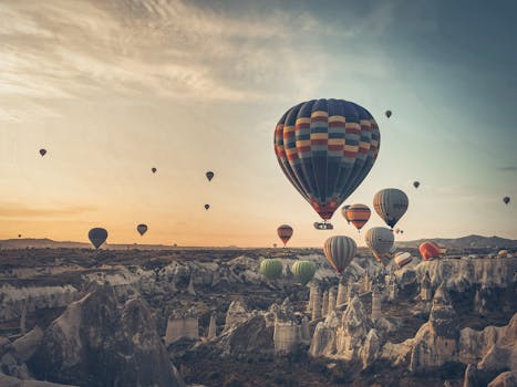 Scenic view of colorful hot air balloons over Cappadocia's unique rock formations at sunrise.
