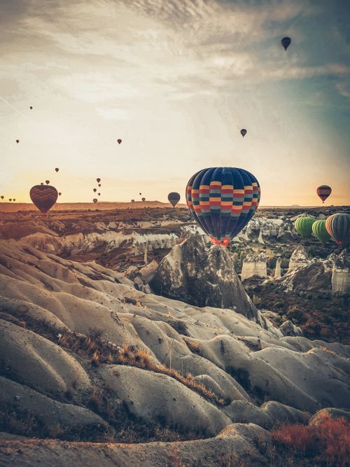 Free Colorful hot air balloons floating over the unique rocky landscape of Cappadocia at sunrise, Türkiye. Stock Photo