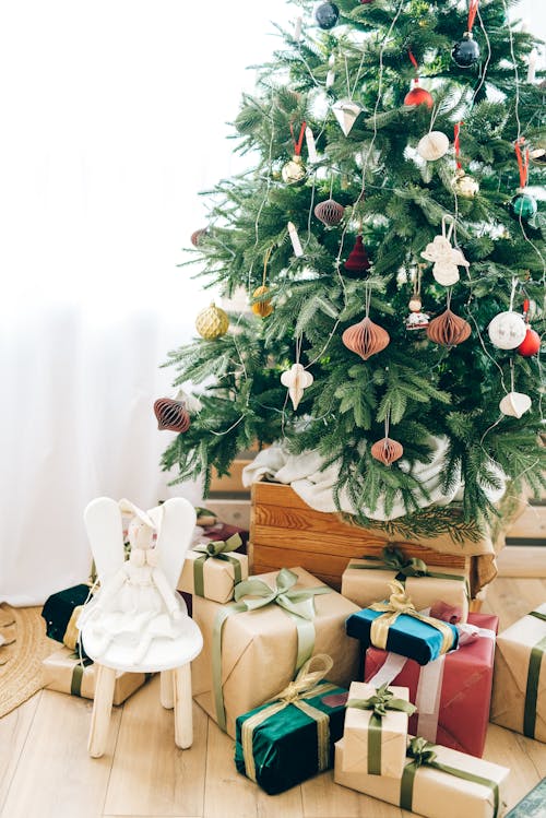 赤と白のギフトボックスと白い革張りのアームチェアと緑のクリスマスツリー
