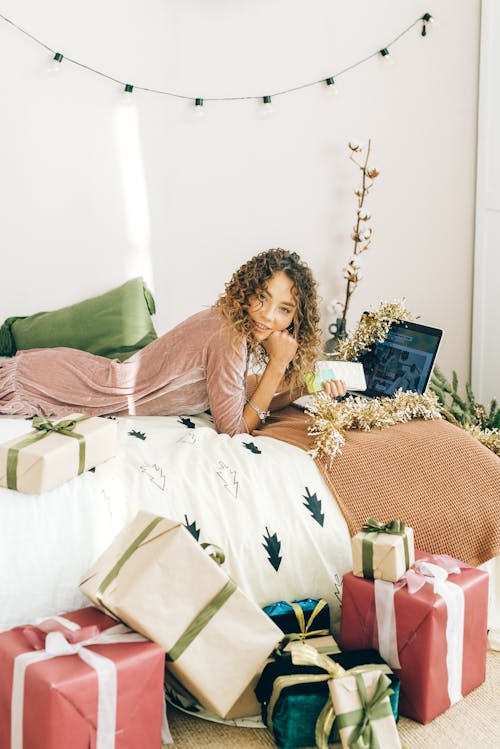 Young Woman Lying on the Bed among Christmas Presents 