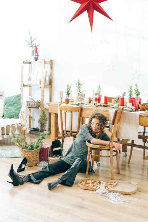 Free A woman rests on a dining chair in a festive indoor setting with pizza and decorations. Stock Photo