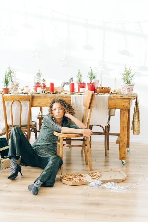 Free Contemplative woman beside a festive dining table with pizza and holiday decor. Stock Photo