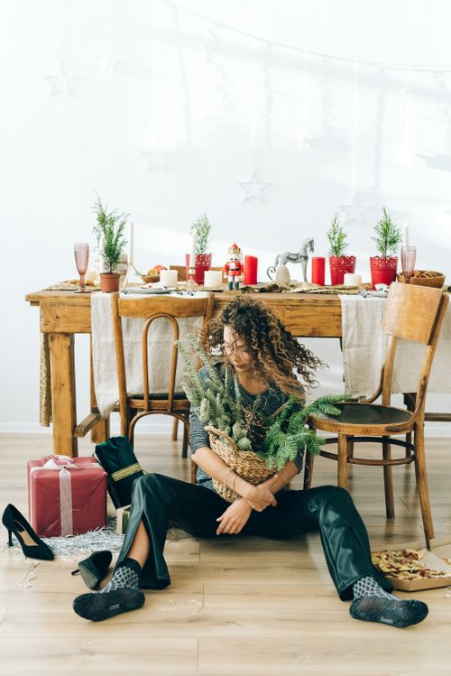 Free Woman sitting surrounded by festive decorations in a cozy holiday setting. Stock Photo