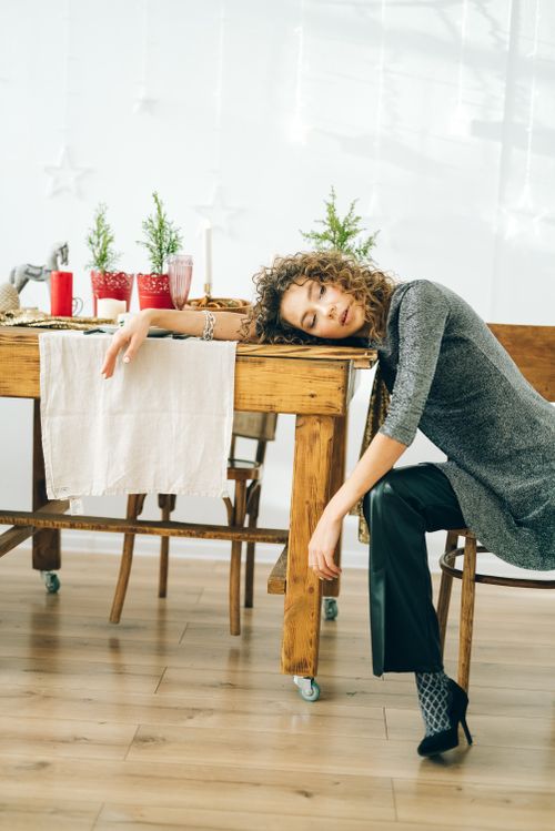 Free Woman with curly hair resting at a festive table, evoking themes of holiday exhaustion and relaxation. Stock Photo