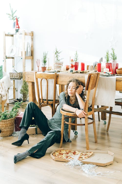 бесплатная Женщина в серой рубашке с длинным рукавом сидит на коричневом деревянном стуле Стоковое фото