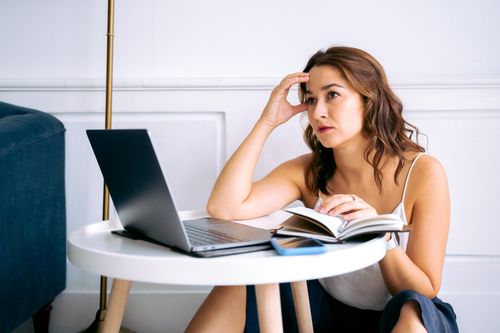 Free A stressed woman sitting at a desk with a laptop and notebook, reflecting work burnout. Stock Photo