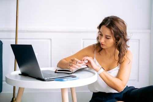 Macbookを使用して白いタンクトップの女性