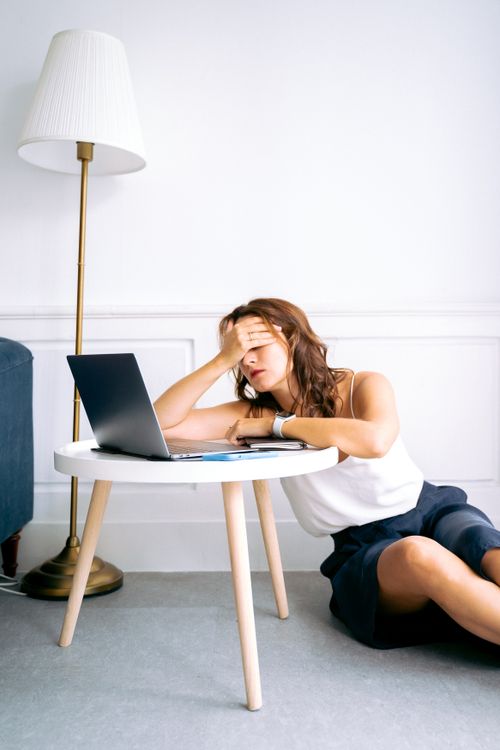 Free A woman showing signs of fatigue while working remotely at a laptop indoors. Stock Photo
