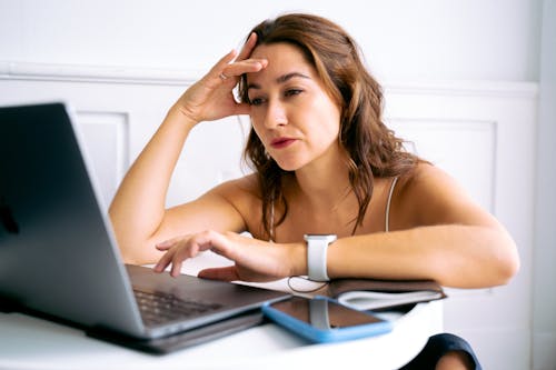 Woman With Hand on Head Using Laptop 