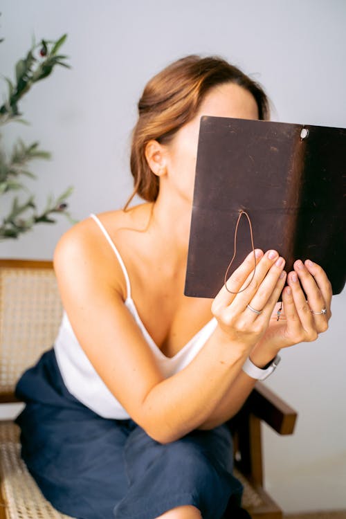 Free A Brown Notebook Covering the Person's Face Stock Photo