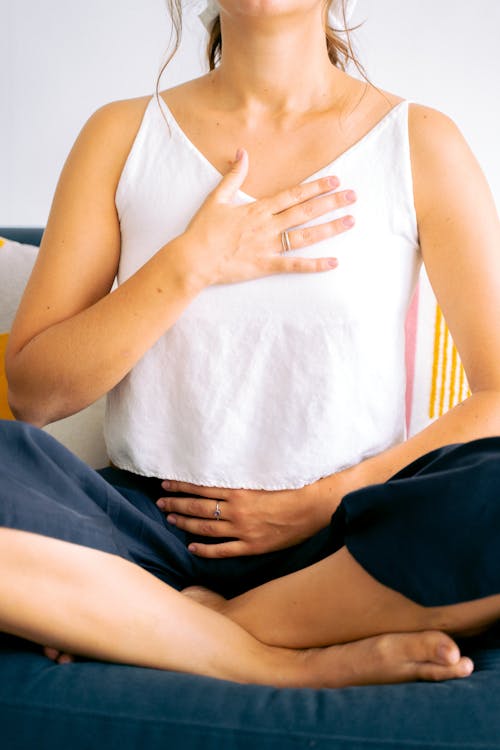 Free Woman in White Top Sitting With Hand on Chest and Belly Stock Photo