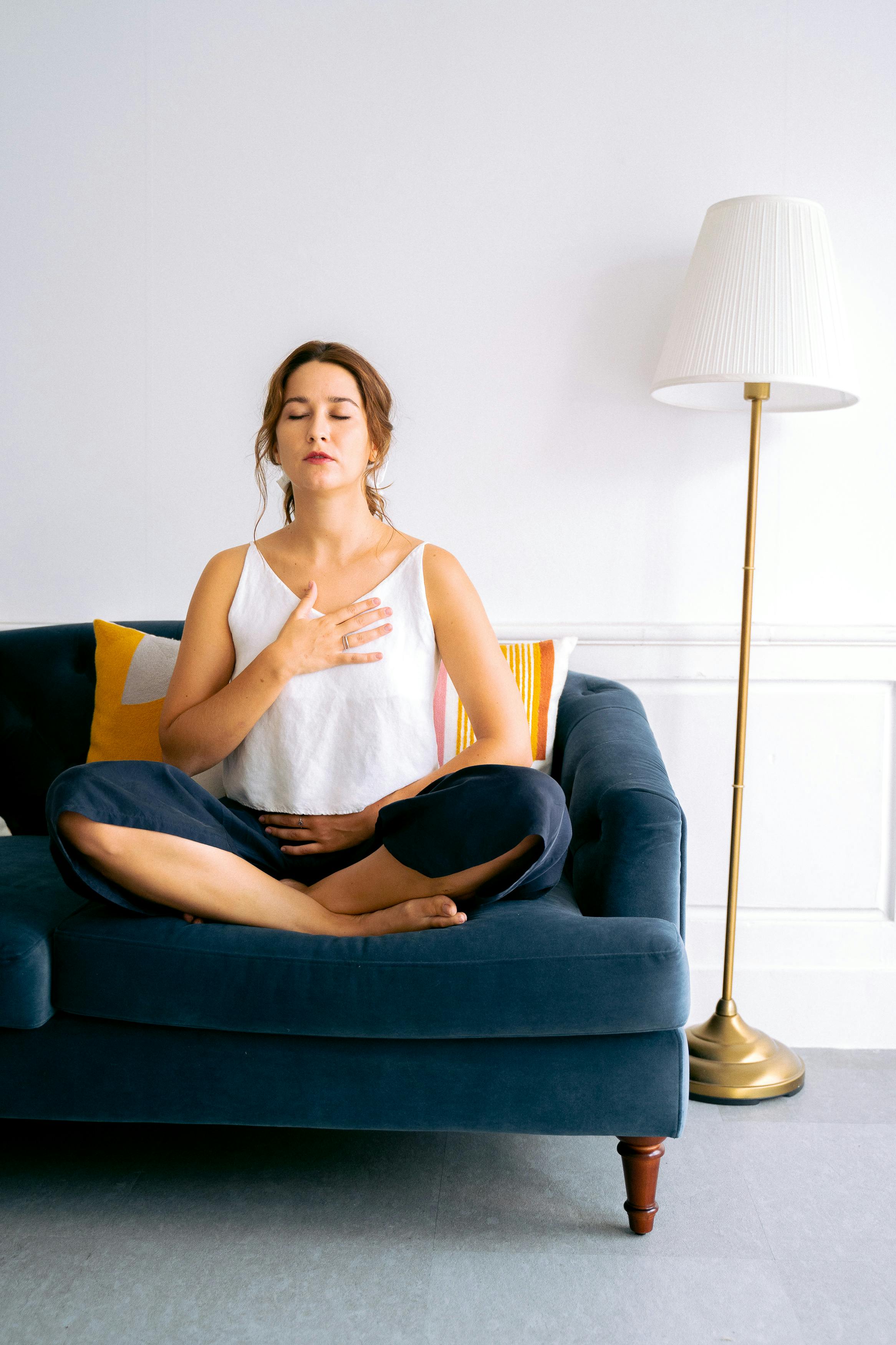 Woman in White Top Sitting on Blue Sofa Chair With Eyes Closed