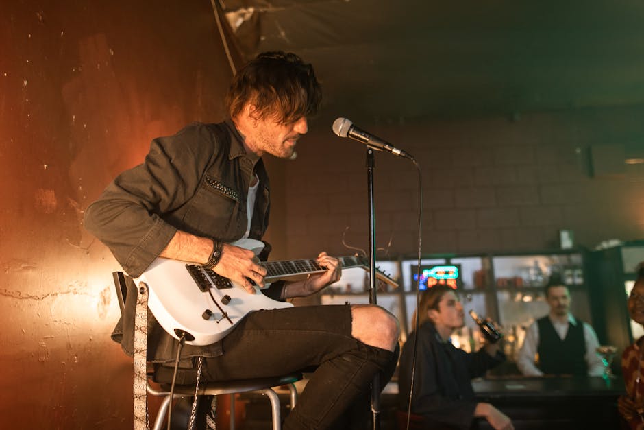 Musician playing acoustic guitar during live performance in intimate bar setting.