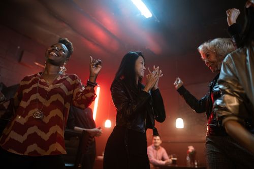 Free A group of women enjoying a fun night out dancing and clapping in a lively nightclub. Stock Photo