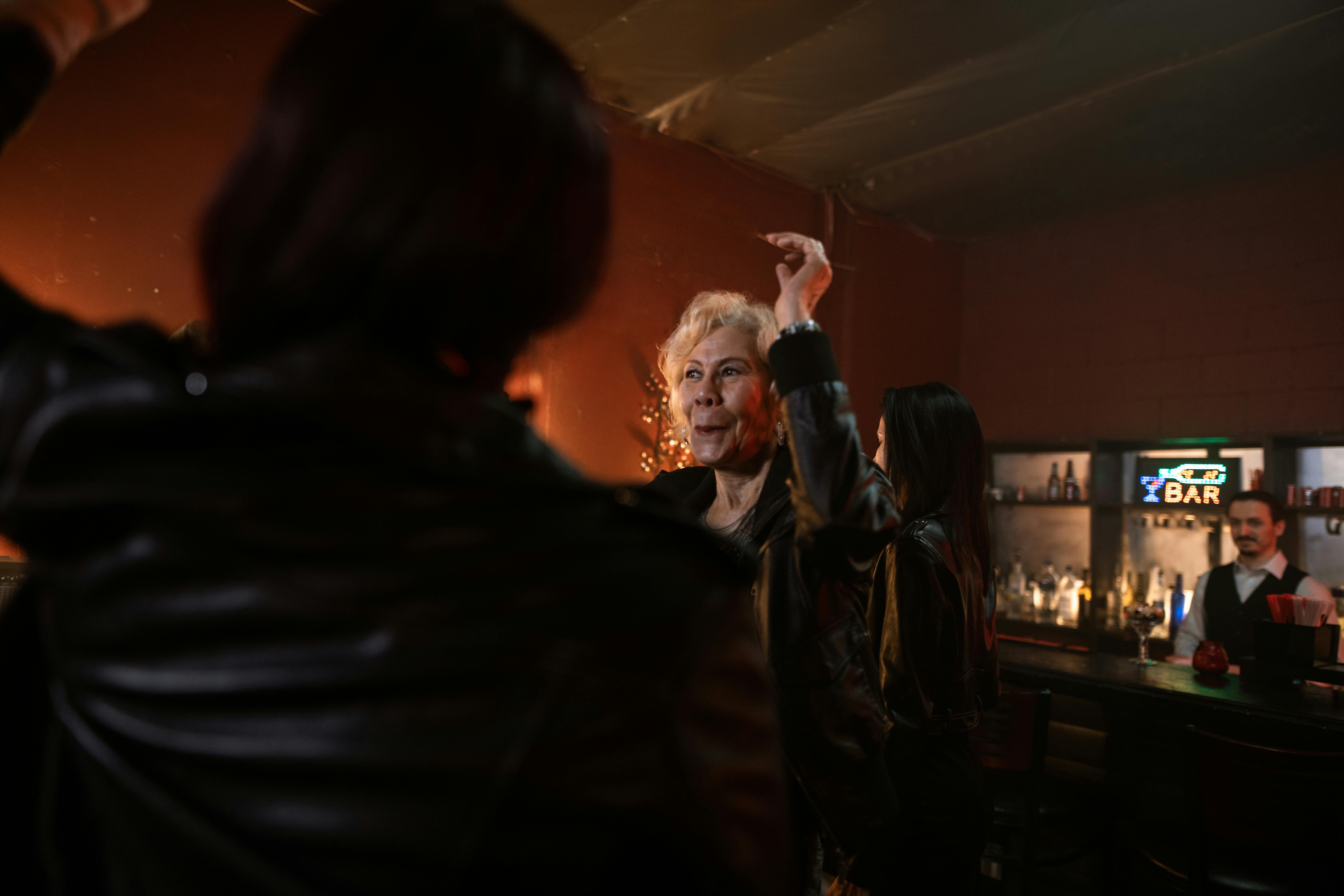 woman in black leather jacket standing with hand raised