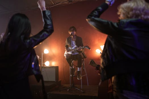 Musician performs live on stage with electric guitar and microphone, captivating excited audience.