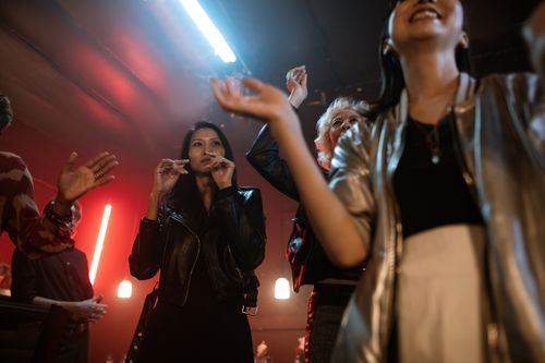 Free Adults enjoying a lively party in an urban nightclub setting with colorful lights. Stock Photo