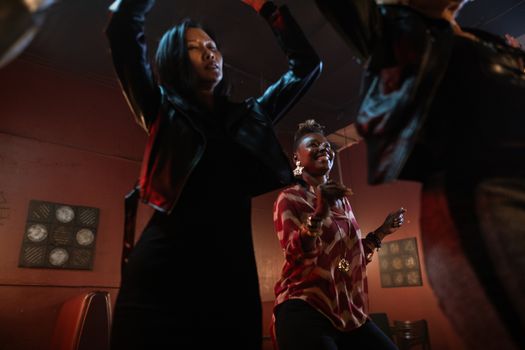 Woman in Black Leather Jacket Dancing Near a Woman in Printed Top