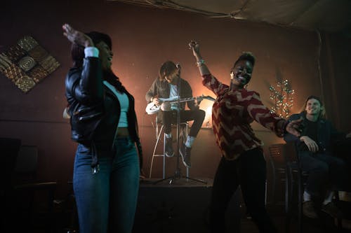 Free Man Playing Guitar on Stage While People Dance Stock Photo