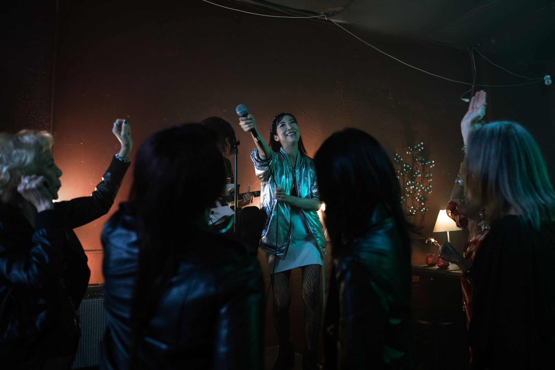 A lively nightclub party scene featuring a female singer performing on stage with a cheering audience.