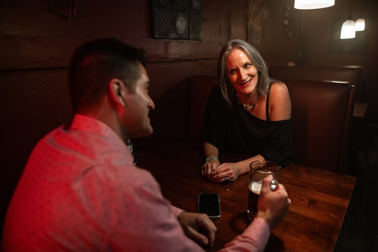 A Woman Talking To A Man Holding A Beer