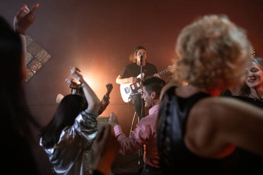 Exciting live music performance with a guitarist and dancing crowd in a vibrant night club.