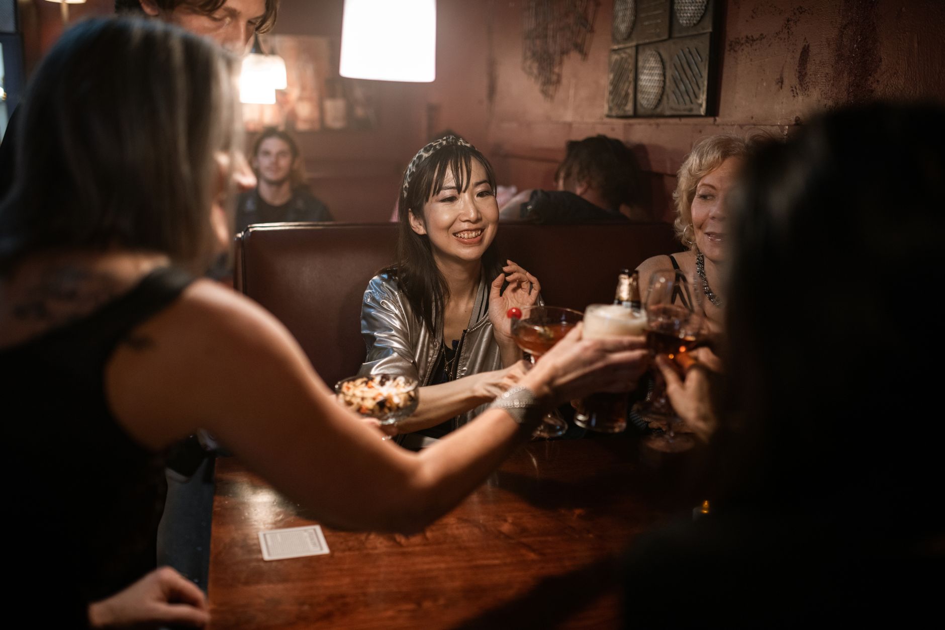 A cheerful group of friends celebrating at a bar, raising their drinks for a toast.