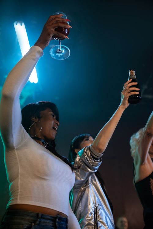 Free Lively night out with friends raising glasses in a vibrant club setting. Stock Photo