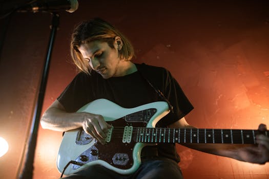 Male musician playing electric guitar at a bar with warm lighting.