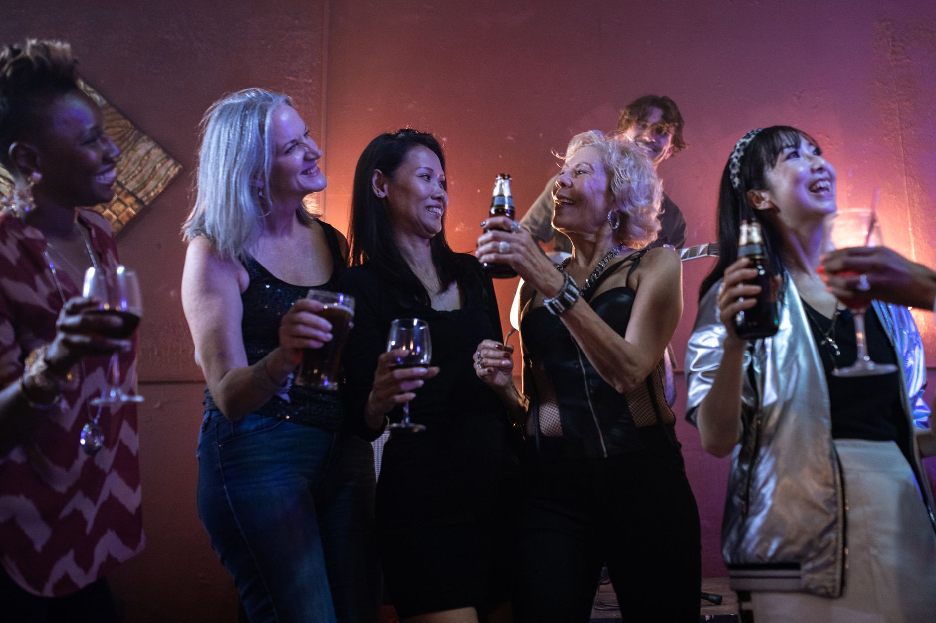 A lively group of diverse women enjoying drinks and fun in a night out setting.