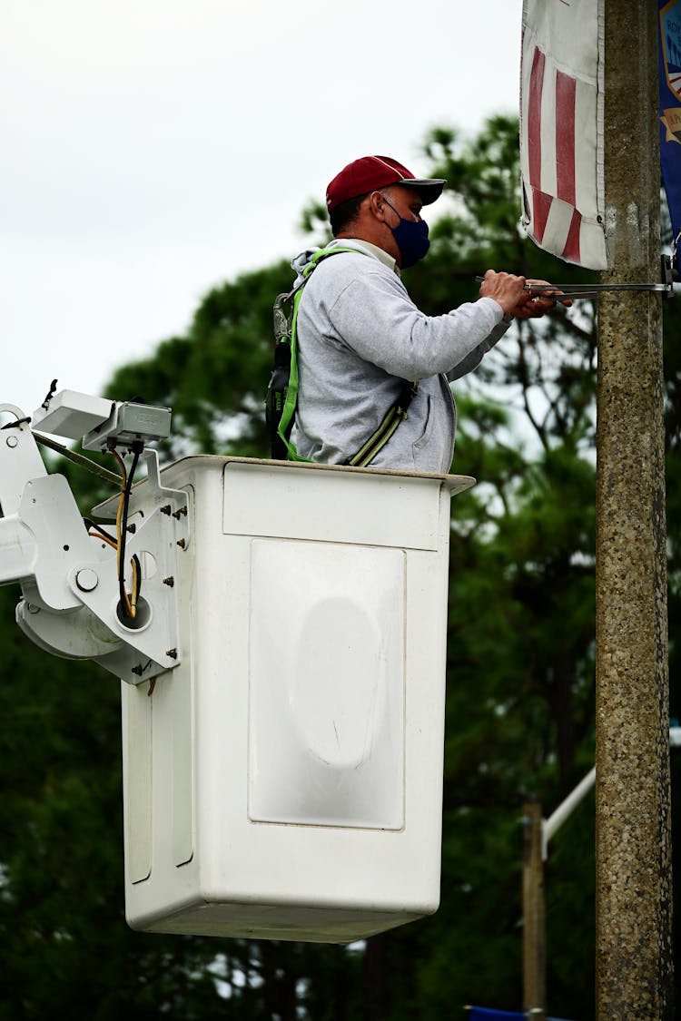 Man In Bucket Lift Mounting Wires On Pillar