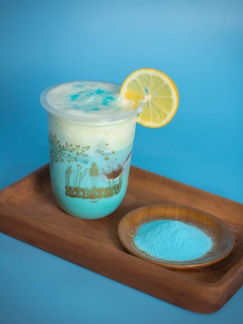 Glass of sweet blue mocktail on wooden tray