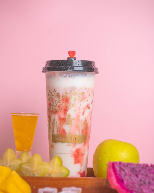 Free Refreshing smoothie in a plastic cup with tropical fruits on a pink background. Stock Photo