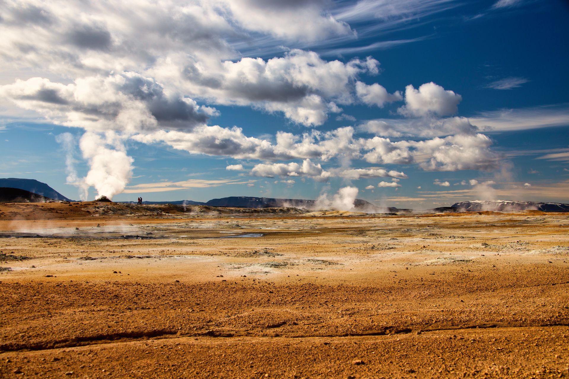 Stunning geothermal landscape in Iceland with steam vents and a vivid blue sky.